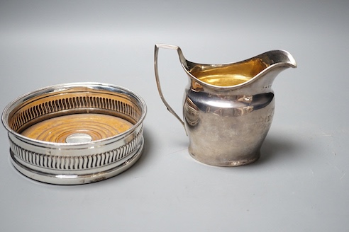 A George III silver mounted wine coaster, Sheffield, 1805, diameter 13.2cm and a George III silver cream jug, with later engraved inscription, London, 1801(a.f.).